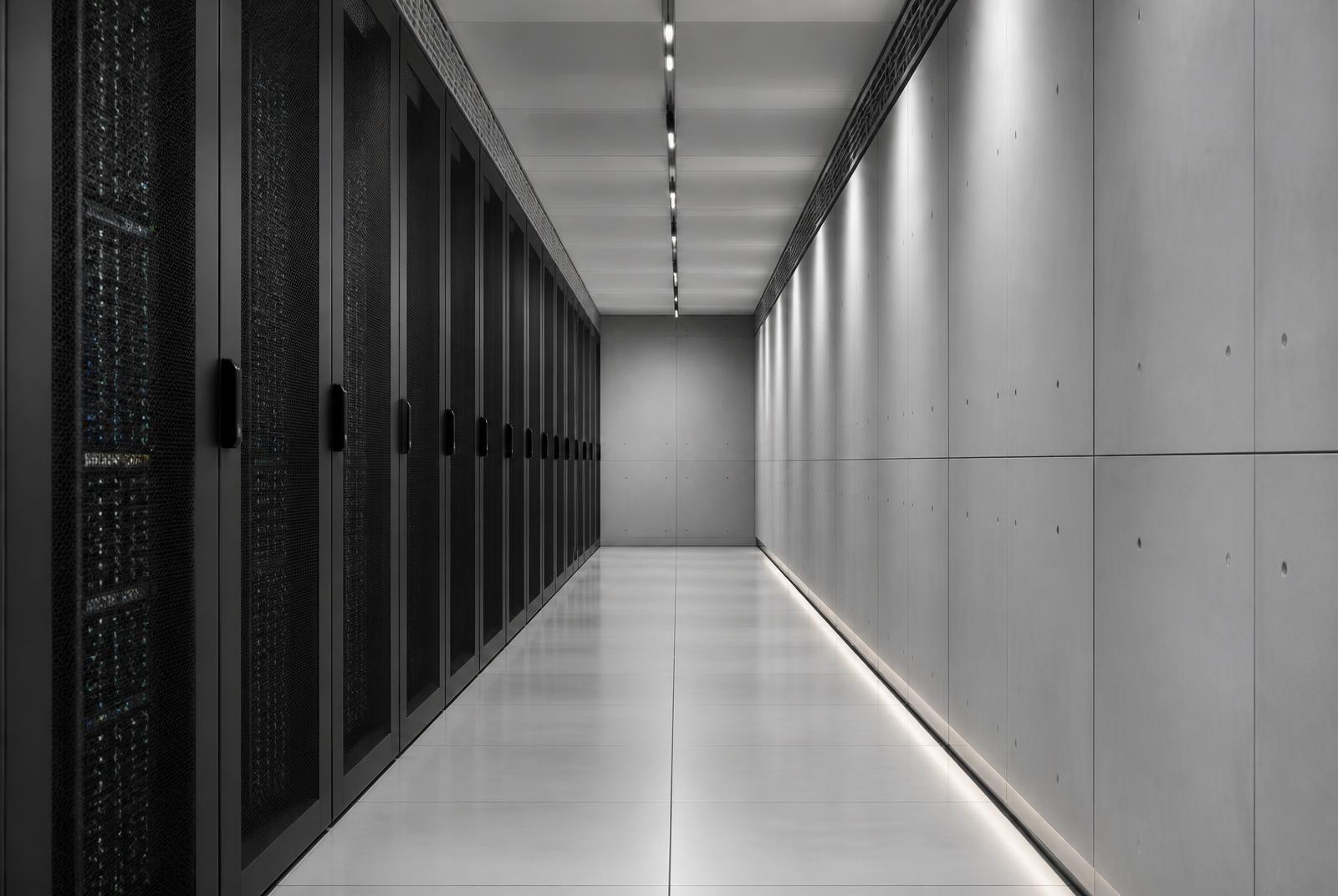 Corridor of server racks in a modern data centre, viewed in cool grey light